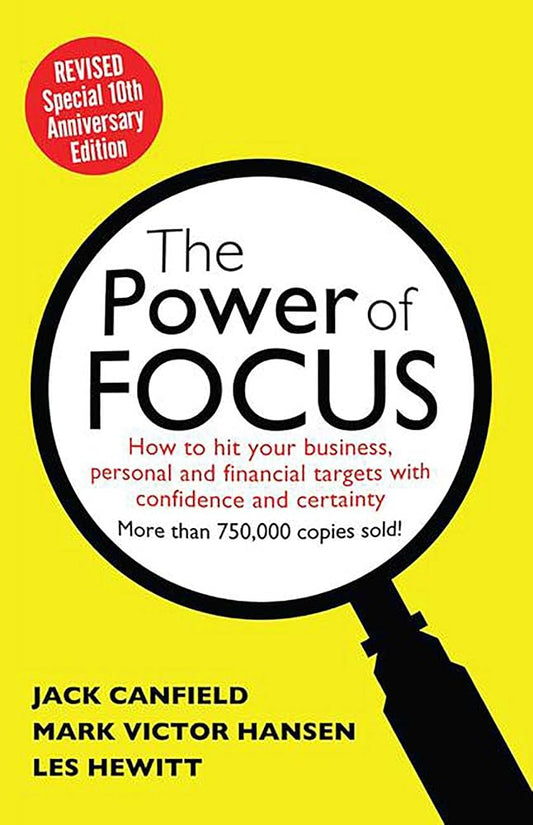 The Power of Focus" by Jack Canfield, Mark Victor Hansen, and Les Hewitt. The cover has a bright yellow background with a large magnifying glass graphic in the center. Inside the magnifying glass, the title "The Power of FOCUS" is displayed prominently in black and white text. Below the title, a subtitle reads "How to hit your business, personal and financial targets with confidence and certainty." A red circular badge in the top left corner states "REVISED Special 10th Anniversary Edition." The bottom of t